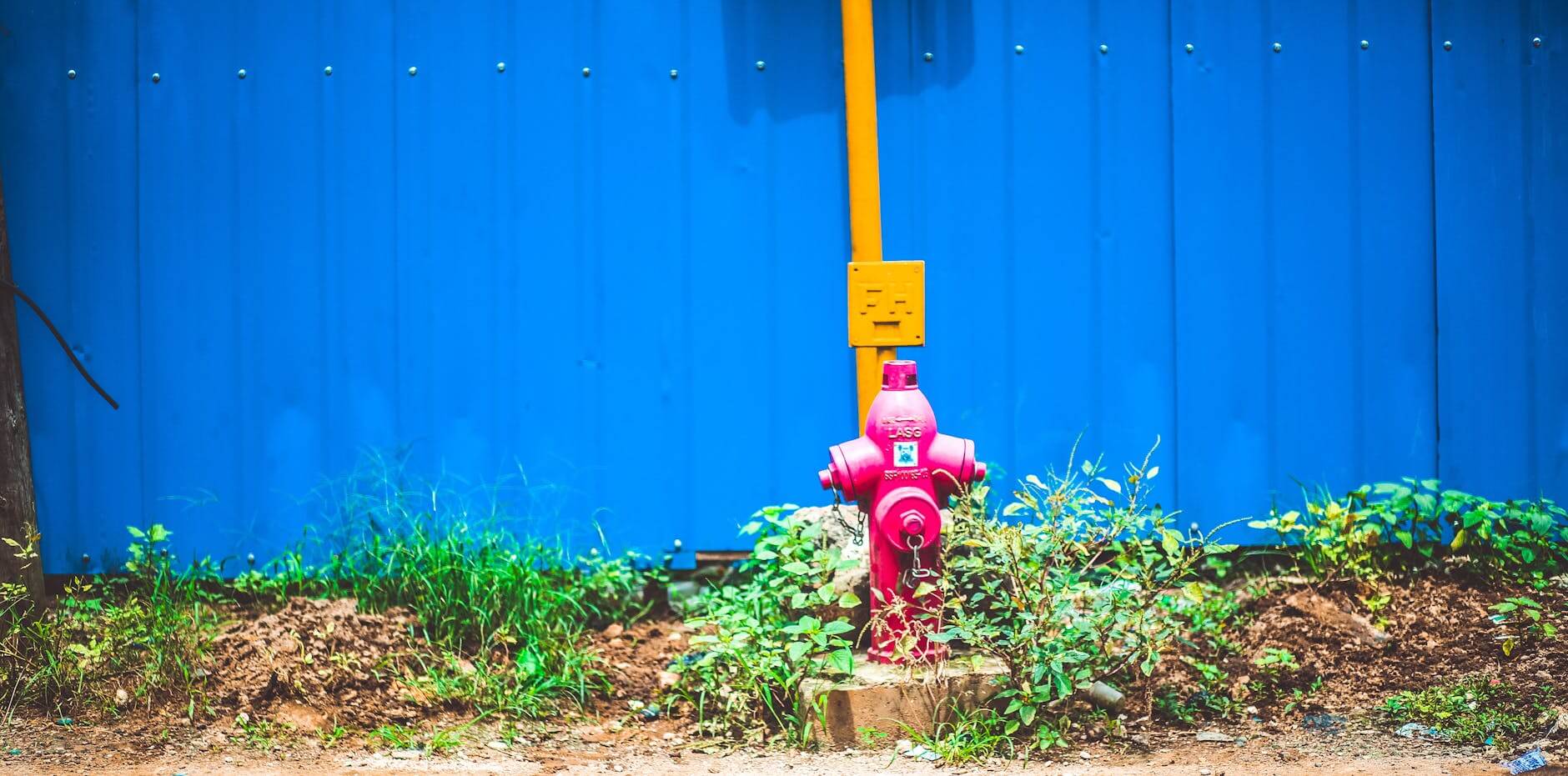 pink steel water pump behind blue fence